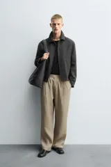 Pantalón negro de corte relajado con cintura elástica ajustable y pliegues en la parte delantera. Presenta bolsillos laterales y bolsillos traseros de parche.