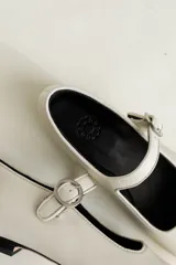 Zapato plano estilo Mary Jane de cuero negro, con punta fina y tira ajustable con hebilla sobre el empeine.