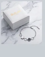 Pulsera de acero con eslabones circulares y dijes en forma de flor esmaltados en blanco y negro.