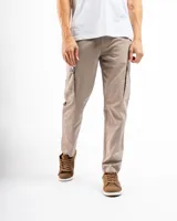 Pantalón cargo slim fit color beige, confeccionado principalmente en algodón con un pequeño porcentaje de spandex para elasticidad. Presenta múltiples bolsillos utilitarios tipo cargo en los muslos.
