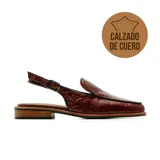 Zapato destalonado de cuero marrón con textura croco, punta cuadrada y taco bajo. Cuenta con una tira ajustable con hebilla en el talón.