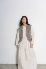 Chaleco tejido de punto en color taupe, con textura rústica y diseño sin mangas. Presenta un corte recto y abierto al frente, ideal para superponer sobre otras prendas.