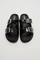 Sandalias planas de mujer con doble tira ancha en el empeine, hebillas metálicas plateadas y textura símil cocodrilo.
