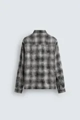 Camisa de corte relajado confeccionada en tejido de algodón con estampado de cuadros en tonos marrones y beige. Presenta cuello solapa, manga larga con puños abotonados, bolsillo plastrón en el pecho y cierre frontal con botones.