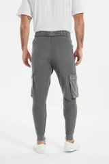 Babucha de estilo cargo en color gris, con cintura elástica ajustable mediante cordón, bolsillos laterales con solapa y puños elásticos en los tobillos.