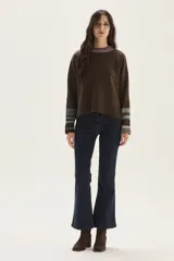 Sweater tejido de lambswool color beige, con cuello redondo y puños acampanados con rayas de colores (marrón, mostaza, bordó y beige). Incluye un detalle de temporada hecho a mano en la espalda.