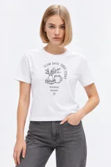 Remera de manga corta de algodón, color blanco, con cuello redondo y estampado frontal estilo collage con gráficos y texto en tono bordó.