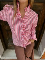 Camisa de manga larga con estampado de rayas verticales en color rojo y blanco. Presenta cuello alto con volados, cierre frontal con botones y detalles de volados en la solapa y en los puños.