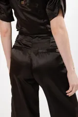 Pantalón negro de seda con tiro alto, corte recto, pinzas en la pretina y tajos en el ruedo.