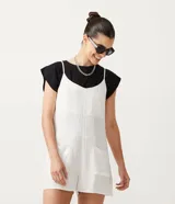 Enterito corto de tirantes finos ajustables, color blanco con rayas verticales finas, escote en V y bolsillos delanteros.