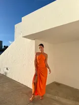 Vestido largo naranja de crepé con escote en pico y falda tipo pareo regulable.
