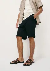 Bermuda cargo negra, de corte recto y largo hasta la rodilla, con bolsillos laterales tipo parche.