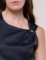 Blusa de satén color negro, de corte fluido, con escote asimétrico y un aro metálico decorativo en el hombro.