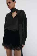 Bermuda de tiro alto de terciopelo negro, con cintura elástica y detalle de encaje tono sobre tono en el ruedo.