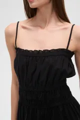 Vestido corto de algodón color blanco, con breteles finos tipo lencero, escote recto con detalle de volado y cintura con elástico fruncido. La falda presenta un diseño holgado con volado en el ruedo.