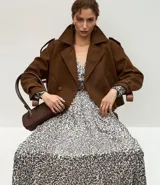 Vestido midi de tejido satinado con estampado abstracto, escote en V, mangas largas con volumen y hombreras estructuradas. Incluye un cinturón con hebilla para marcar la cintura y falda fluida con recortes.