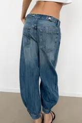 Jeans de tiro medio y diseño balloon, color azul denim con efecto lavado, cinco bolsillos, cierre frontal con cremallera y botón metálico, y bajos acabados en puño.