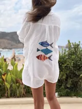 Camisa de lino blanca, de manga larga y corte oversize, con detalle de peces bordados en la espalda.