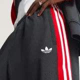 Pantalón Adidas Originals de corte holgado, confeccionado en tejido de malla color negro. Presenta las icónicas tres tiras laterales en color rojo y el logo del trébol bordado en la pierna.