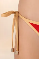 Calzón de bikini rojo con ribetes dorados y diseño de tiritas laterales.