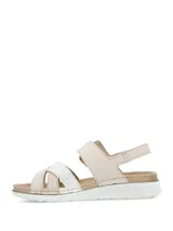 Sandalias planas de mujer en color beige, con tiras cruzadas en el empeine, una de ellas con textura plateada brilhante. Cuenta con tira ajustable al tobillo mediante hebilla con efecto carey y suela blanca con base dentada.