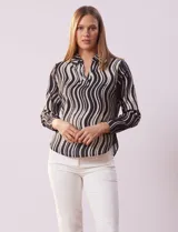 Blusa de gasa estampada en blanco y negro, marca Sioni. Tiene cuello con solapa y escote en V, mangas largas con puño fruncido.