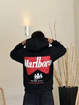 Canguro negro con capucha, de corte boxy, con estampa gráfica en la espalda que recrea el logo de Marlboro en rojo y blanco, junto con el escudo de Philip Morris y la leyenda 'Smoking kills' y 'FILTER BLACK'.