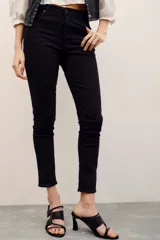 Jean skinny de tiro medio color negro, confeccionado en algodón con elastano, con cierre y botón.
