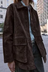 Cazadora de ante color marrón oscuro, con cuello solapa, manga larga y cierre frontal de botones. Incluye dos bolsillos delanteros de plastrón con solapa.