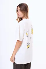 Remera de algodón color blanco, de corte holgado y manga corta, con estampado gráfico en la espalda que incluye dibujos de limones, una jarra, un vaso y un lazo.