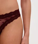 Kit de tres bombachas tipo bikini confeccionadas en encaje floral con forro de algodón. El set incluye una prenda roja, una bordó y una negra.