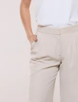 Pantalón de vestir de tiro alto, color beige, con corte wide leg y pinzas frontales.