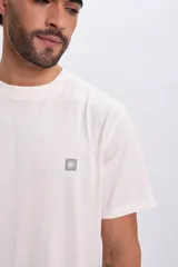 Remera de manga corta oversize color blanco, con cuello redondo y un pequeño parche bordado en forma de sol en el pecho.