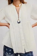 Blusa blanca con cuello mao y escote en V, de manga corta y corte amplio con fruncido frontal.