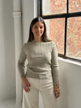 Sweater de punto color visón con diseño de trenzas verticales, cuello redondo y mangas largas.