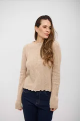 Buzo de tejido de punto color beige, con cuello redondo, manga larga y terminación de ruedo con diseño ondulado.