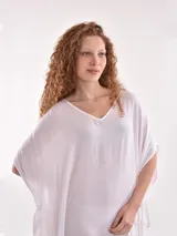 Vestido de tela fluida color marrón medio, con escote en V y mangas cortas tipo kimono. El ruedo es asimétrico con aberturas laterales.