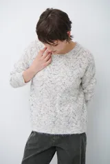 Buzo de tejido de punto con cuello redondo, mangas largas y textura jaspeada en tonos neutros.