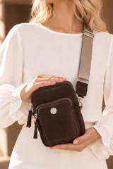 Bandolera pocket bag de cuero vacuno color suela, con bolsillo frontal con cierre y detalle de placa metálica con logo. Cuenta con correa de cinta ancha regulable y herrajes metálicos plateados.