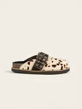 Zueco de cuero vacuno con estampado animal print tipo vaca, con hebilla decorativa metálica con ojales y suela de corcho con vira reforzada.