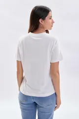 Remera básica de manga corta color crudo con estampa frontal circular que incluye flores en tonos celestes y la inscripción en color bordó "L'Atelier Botanique Fleurs La beauté de la nature".