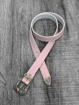 Cinto de cuero sintético color rosa pastel con hebilla y puntera metálicas con diseño labrado.