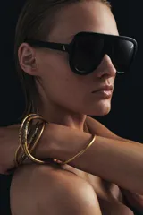 Pack de seis pulseras rígidas de metal dorado con acabado mate, algunas de ellas presentan incrustaciones de cristales oscuros en secciones específicas.