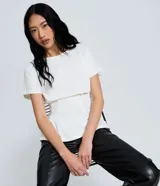 Blusa peplum blanca de algodón, con cuello redondo, mangas cortas, ajuste en la cintura y diseño con pliegues.