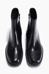 Botas cortas negras de cuero con acabado brillante y textura arrugada, punta cuadrada y taco bajo y ancho.