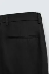 Pantalón de corte wide fit confeccionado en algodón, con pliegues frontales dobles, bolsillos laterales y bolsillos traseros de doble vivo. Presenta cierre frontal con cremallera y botón.