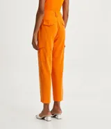Pantalón cargo de viscosa color naranja, con cintura alta y cierre por enganche doble y botones. Cuenta con bolsillos delanteros, laterales y traseros, y pliegues delanteros.
