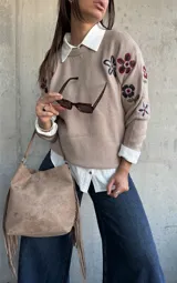 Sweater de punto color beige con cuello redondo y diseño de flores bordadas en tonos oscuros en el frente y las mangas.