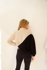 Buzo de lana de cordero italiano color beige y negro, con cuello cisne y corte holgado.