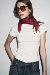 Pañuelo cuadrado de seda y viscosa, color verde oliva con estampado floral y de paisley en tonos rojizos, verdes y marrones. Borde con línea fina en color bordó.